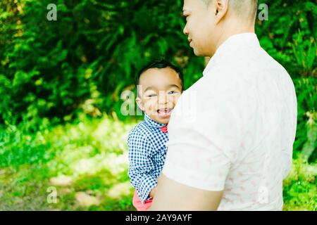 Vista da dietro di un padre che porta il suo bambino sorridente Foto Stock