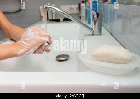 Il bambino con attenzione si lava le mani con sapone, in primo piano di una barra di sapone Foto Stock