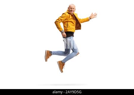 Scatto a tutta lunghezza di un uomo calvo felice in una giacca gialla sorridente e salto isolato su sfondo bianco Foto Stock