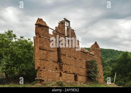 Muro di mattoni con intonaco di argilla adobe e telaio della finestra rotto di vecchia casa rurale in rovina Foto Stock