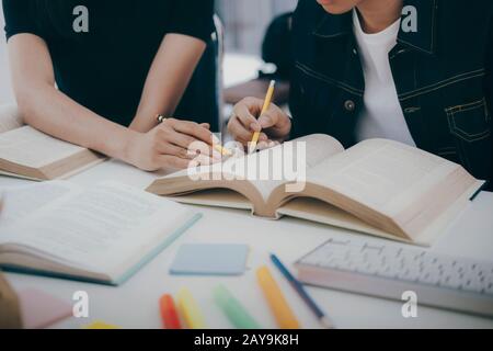 Apprendimento, istruzione e concetto scolastico. Giovane donna e uomo che studiano per una prova o un esame. Tutor libri con amici. Il campus dei giovani studenti aiuta la frie Foto Stock