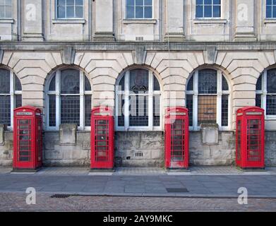 una linea di quattro tradizionali scatole telefoniche rosse britanniche fuori da un vecchio edificio dell'ufficio postale a blackpool Foto Stock