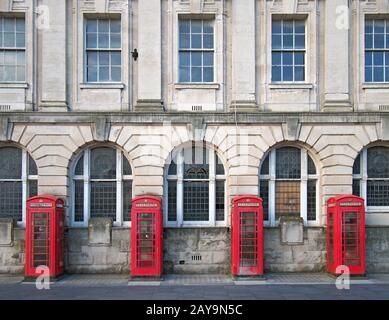 una linea di quattro tradizionali scatole telefoniche rosse britanniche fuori da un vecchio edificio dell'ufficio postale a blackpool Foto Stock