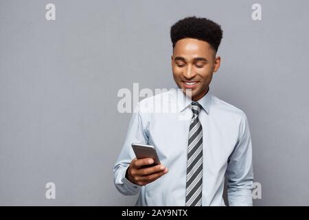 Il concetto di business - Happy bello professional african american businessman sms sul cellulare. Foto Stock