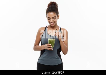 Concetto sano e Fitness - bella donna Africana americana in abbigliamento fitness bere sano bevanda vegetale. Isolato su Foto Stock