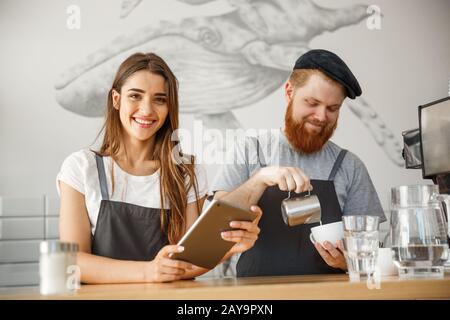 Caffè il concetto di Business - Allegro baristi guardando loro compresse per ordini online nella moderna caffetteria. Foto Stock