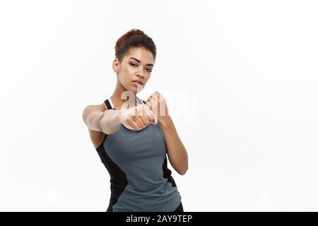 Concetto sano e Fitness - ritratto di donna African American punzonatura in aria con il viso fiducioso. Isolato su sfondo bianco Foto Stock