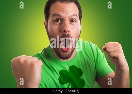 Uomo che indossa il verde t-shirt con shamrock stampati su di essa celebra la festa di San Patrizio. Foto Stock