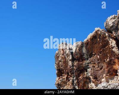 uno sperone roccioso frastagliato ruvido contro un cielo blu brillante illuminato dal sole Foto Stock