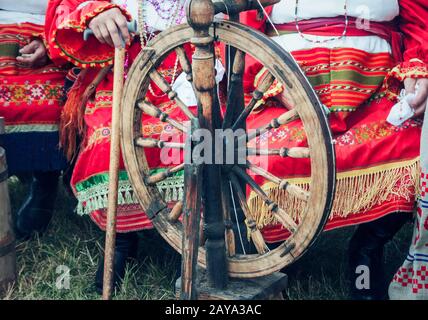 In legno antico ruote di filatura e di una donna in costume nazionale. Foto Stock