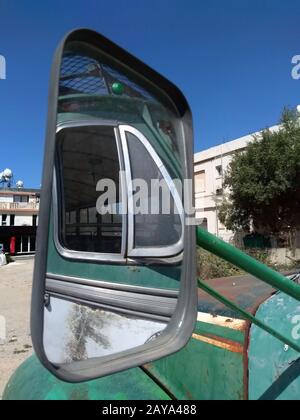 specchio di un vecchio autobus verde con riflessione della finestra laterale in una piazza in un villaggio di cipro Foto Stock