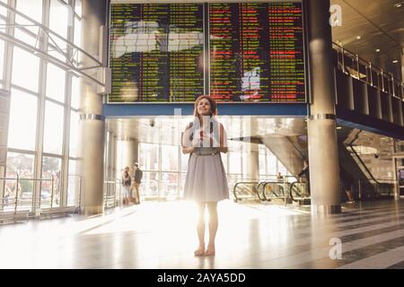 Viaggio a tema e tranosport. Bella giovane donna caucasica in abito e zaino in piedi all'interno della stazione ferroviaria o del terminal loo Foto Stock