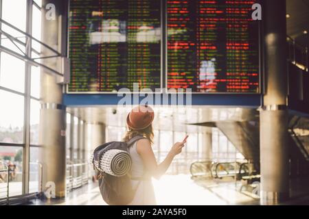 Viaggio a tema e tranosport. Bella giovane donna caucasica in abito e zaino in piedi all'interno della stazione ferroviaria o del terminal loo Foto Stock