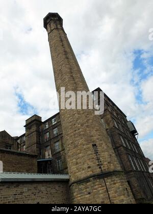 vecchio edificio industriale di pietra mulino con alto camino in huddersfield west yorkshire Foto Stock