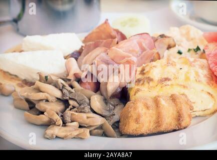 La prima colazione :: uova strapazzate, prosciutto , funghi e verdure. Foto Stock