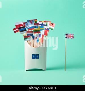 Diverse bandiere di carta in una scatola di cartone con un cartello UE e bandiera della Gran Bretagna a parte su sfondo verde con spazio per le copie. L'uscita Foto Stock