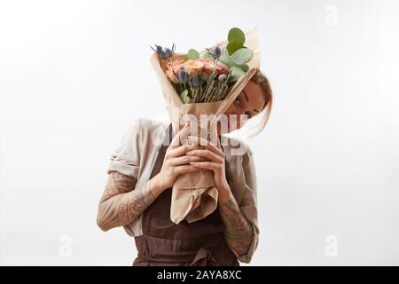 La ragazza sorridente tiene grappolo di saluto dai fiori profumati bei che vivono corallo colorato su uno sfondo grigio. Spazio di copia. Concetto Foto Stock