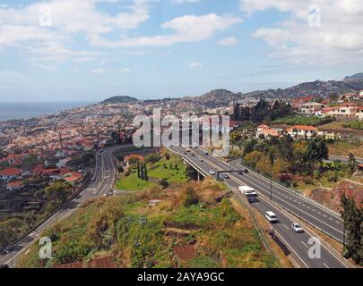 Una vista aerea della città di funchal che mostra il traffico sulla principale autostrada VR1 che corre nella città con la costa visibile nel Foto Stock