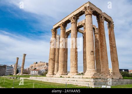 Rovine dell'antico tempio di Zeus Olimpio ad Atene con la collina dell'Acropoli sullo sfondo Foto Stock