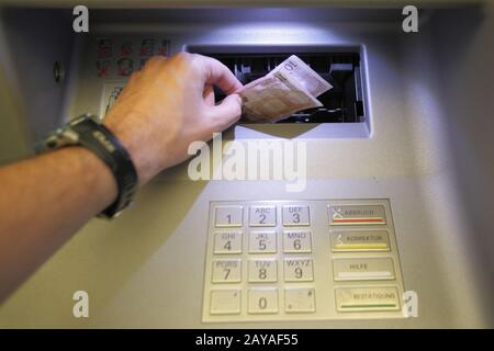 Maschio prende mano euro denaro da un distributore automatico. Pagamento di denaro, finanza transazione e concetto di economia. Foto Stock