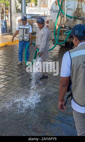 Puerto Escondido, Oaxaca, Messico - I Lavoratori spazzano una strada vicino alla spiaggia principale. Foto Stock