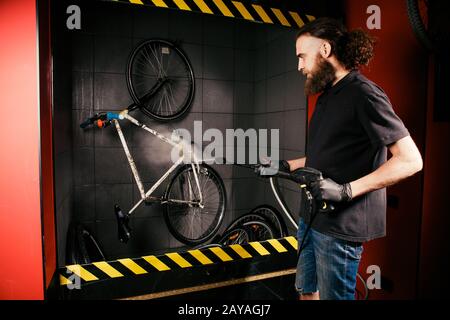 Servizi lavaggio professionale di una bicicletta in officina. Primo piano di mano giovane uomo caucasico elegante che fa la pulizia della bicicletta Foto Stock