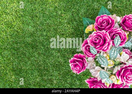 Fiori di plastica su erba verde Foto Stock