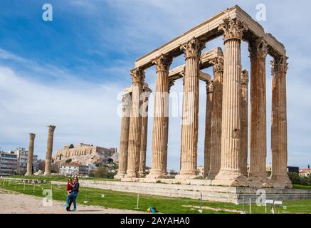 Turisti fotografati di fronte al Tempio Greco di Zeus Olimpio con l'Acropoli di Atene sullo sfondo Foto Stock