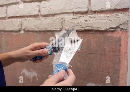 Stuccatore funziona con due spatole per applicazione di intonaco sulla parete Foto Stock