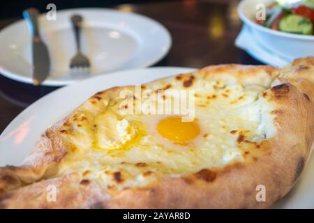 Khachapuri in ristorante georgiano - formaggio nazionale georgiano prodotto di pane, torta farcita con formaggio e uova - Adjara Khachapuri Foto Stock