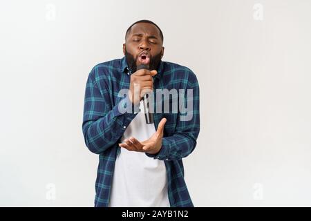 Ritratto di Allegro chic positivo bello uomo africano tenendo il microfono a cantare il canto. Isolato su sfondo bianco. Foto Stock