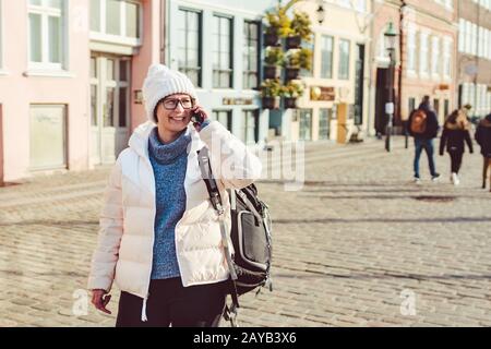 La ragazza turistica caucasica usa il telefono, smartphone chiamata a mano su Copenhagen Nyhavn, l'Europa ben nota attrazione turistica. Donna wom Foto Stock