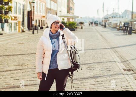 La ragazza turistica caucasica usa il telefono, smartphone chiamata a mano su Copenhagen Nyhavn, l'Europa ben nota attrazione turistica. Donna wom Foto Stock