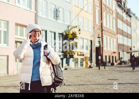 La ragazza turistica caucasica usa il telefono, smartphone chiamata a mano su Copenhagen Nyhavn, l'Europa ben nota attrazione turistica. Donna wom Foto Stock