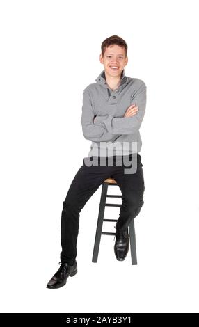 Un bel ragazzo adolescente carino seduto e sorridente Foto Stock