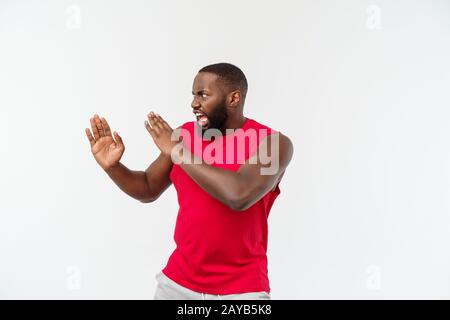 Divertente e giocoso adulto americano africano guy standing in profilo in arti marziali pongono in rilievo con palme, accigliata e fissando. Foto Stock