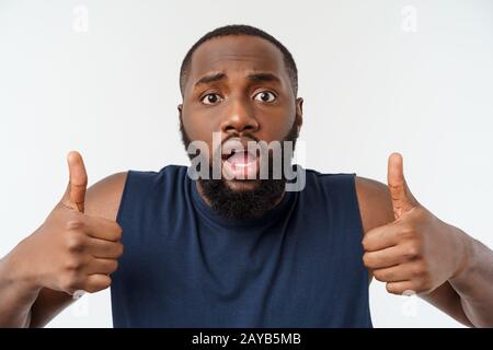 Giovane americano africano uomo su sfondo isolato indossando sport usura sorridente con la faccia felice guardando con il pollice verso l'alto. Foto Stock