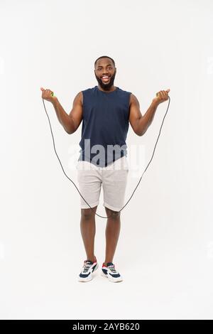 Colpo di uomo maschile corda da salto. Muscoloso giovane esercitando con salto con la corda contro uno sfondo grigio Foto Stock