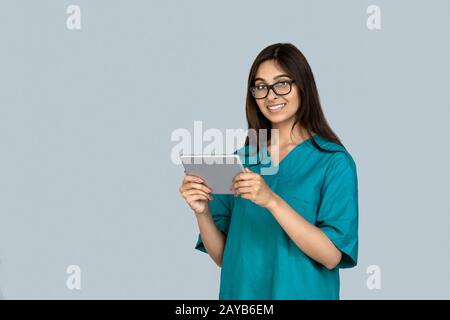 Giovane donna indiana adulta in uniforme medico che tiene un tablet computer Foto Stock