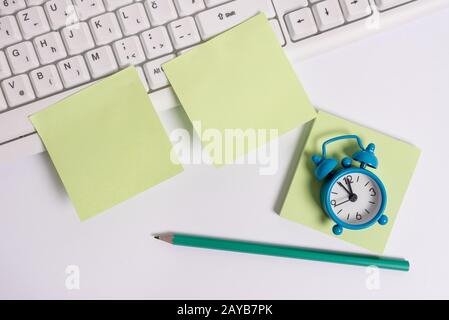 Nota con carta a matita clip orologio su sfondo bianco e tastiera pc. Disposizione piatta sopra la carta per appunti vuota per messaggi di testo Foto Stock