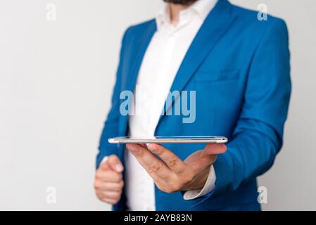 Uomo nella suite blu e camicia bianca tiene il telefono cellulare in mano. Concetto di business con uomo d'affari e telefono cellulare nel Foto Stock
