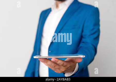Uomo nella suite blu e camicia bianca tiene il telefono cellulare in mano. Concetto di business con uomo d'affari e telefono cellulare nel Foto Stock