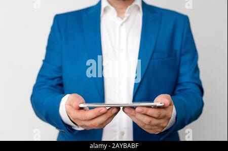 Uomo nella suite blu e camicia bianca tiene il telefono cellulare in mano. Concetto di business con uomo d'affari e telefono cellulare nel Foto Stock