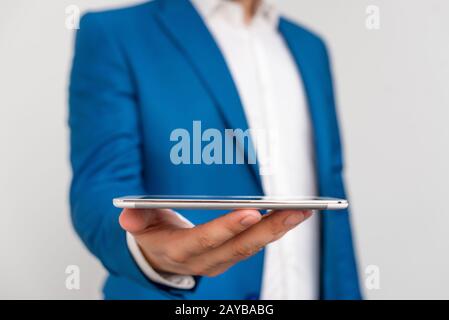 Uomo nella suite blu e camicia bianca tiene il telefono cellulare in mano. Concetto di business con uomo d'affari e telefono cellulare nel Foto Stock