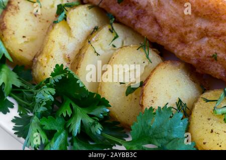 Pesce fritto con patate, verdure e verdure primo piano. Foto Stock