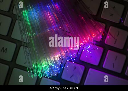 Fibre ottiche colorate illuminate su sfondo scuro. Internet ad alta velocità. Cavo in fibra ottica per il trasferimento dati. Foto Stock