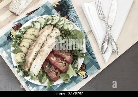 Pesce fritto con patate, verdure ed erbe aromatiche Foto Stock