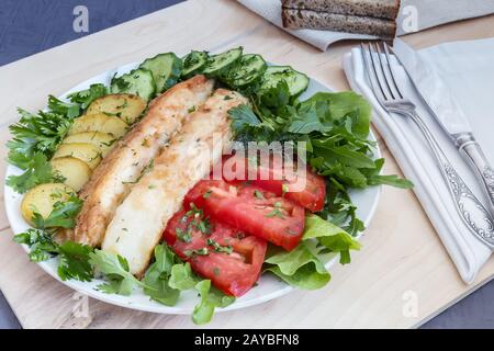 Pesce fritto con patate, verdure ed erbe aromatiche Foto Stock