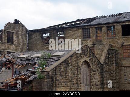 un vecchio grande edificio industriale abbandonato con finestre bruciate e tetto crolante Foto Stock