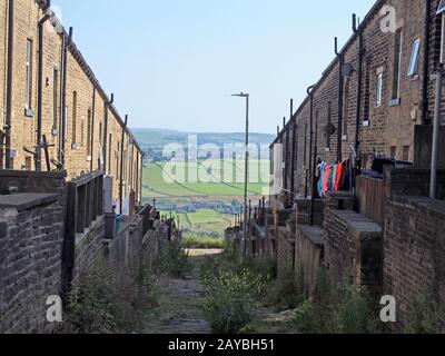 un tipico vicolo settentrionale nello yorkshire occidentale con iarde e linee di lavaggio tra le strade di vecchie case con una vista dei campi Foto Stock